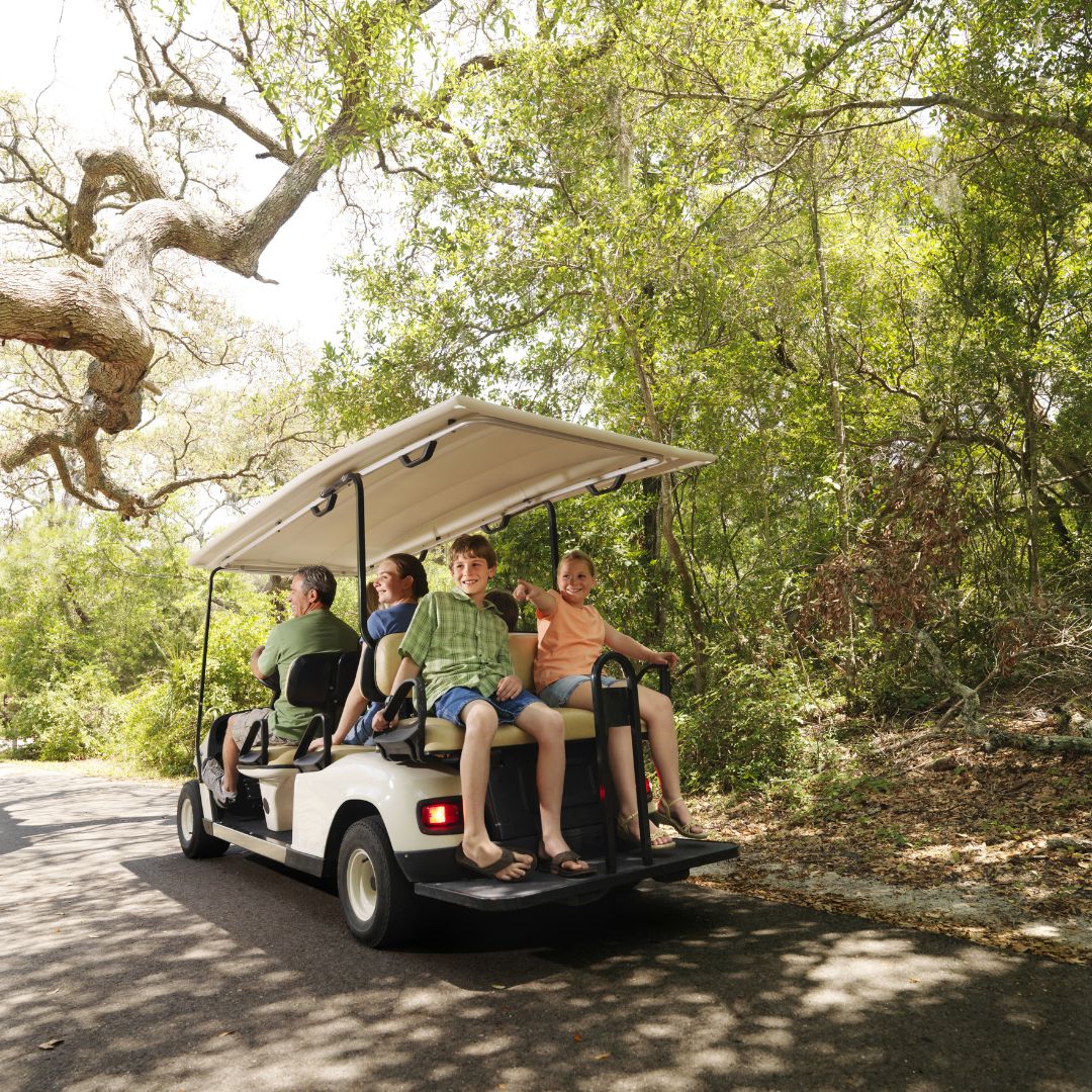 family riding down wooded path on a golf cart