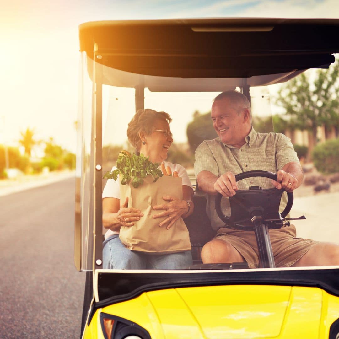 older couple riding on a golf cart