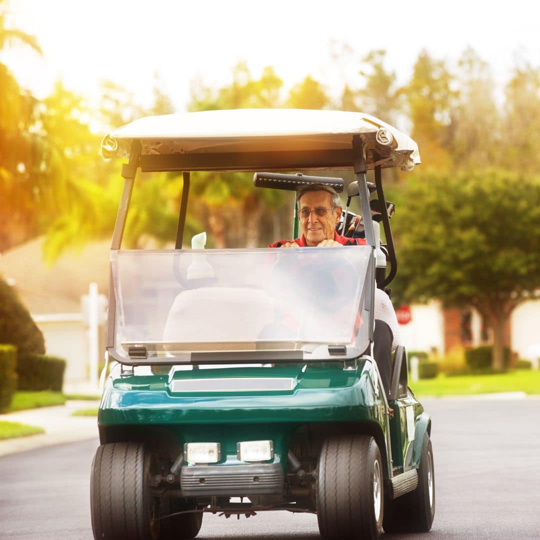 older man driving golf cart